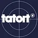 Der weiße Schriftzug „tatort“ und das Erste-Logo stehen vor einem Fadenkreuz mit zwei Kreisen auf dunkelblauem Grund.